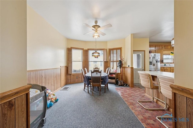 dining space featuring wooden walls and ceiling fan