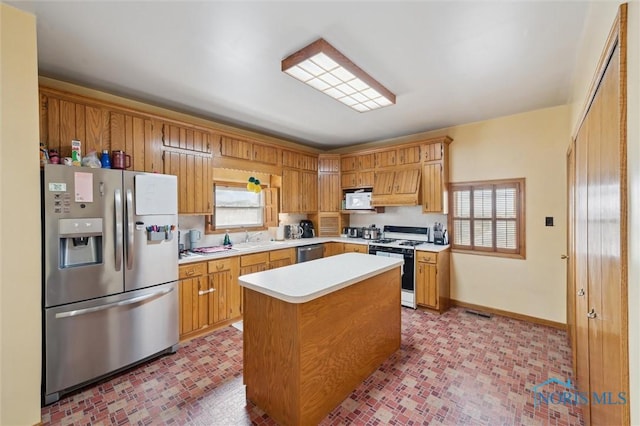 kitchen with a healthy amount of sunlight, appliances with stainless steel finishes, sink, and a kitchen island