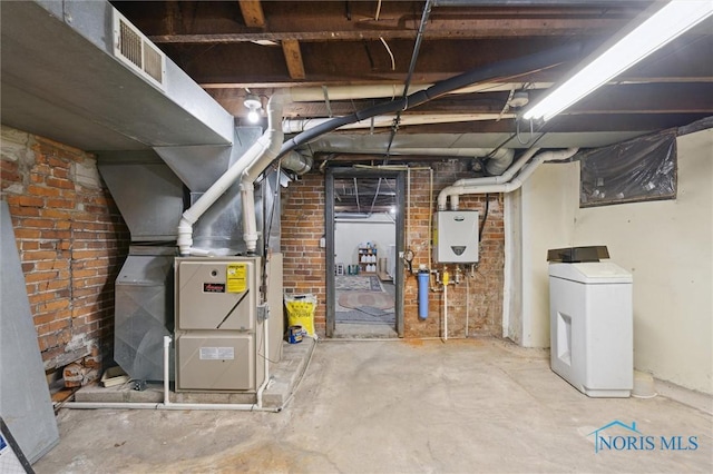 basement featuring brick wall, washer / dryer, heating unit, and tankless water heater