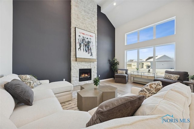 living area featuring baseboards, a fireplace, high vaulted ceiling, and wood finished floors