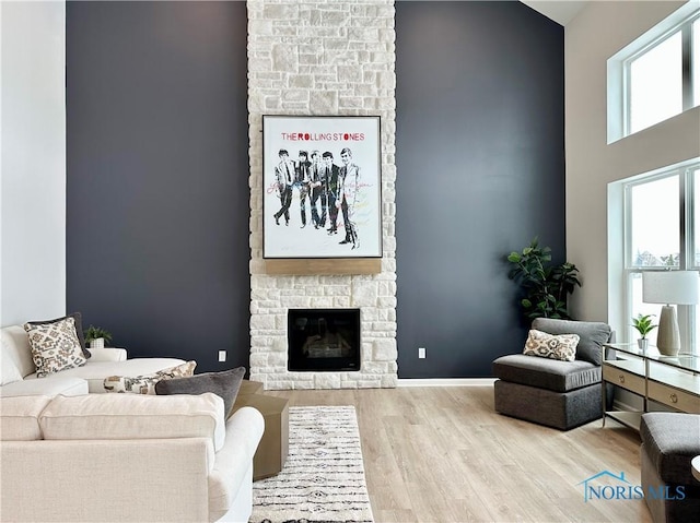 sitting room with a towering ceiling, a fireplace, baseboards, and wood finished floors