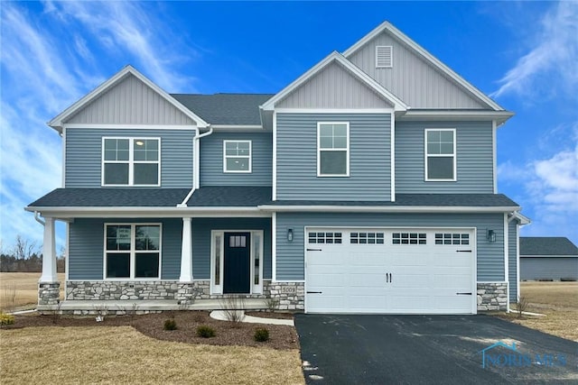 craftsman inspired home featuring aphalt driveway, stone siding, covered porch, and an attached garage