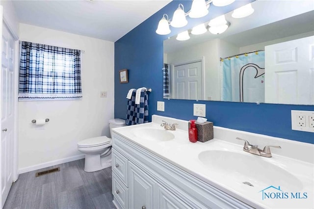 bathroom with toilet, vanity, and wood-type flooring