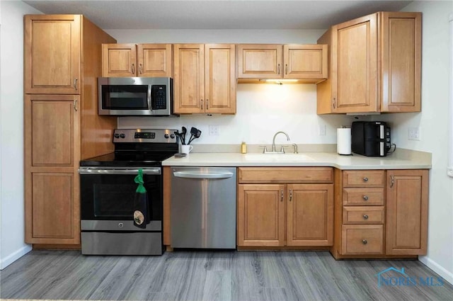 kitchen featuring appliances with stainless steel finishes, sink, and hardwood / wood-style flooring