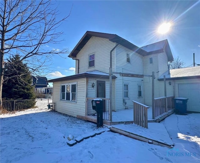 snow covered property with a garage