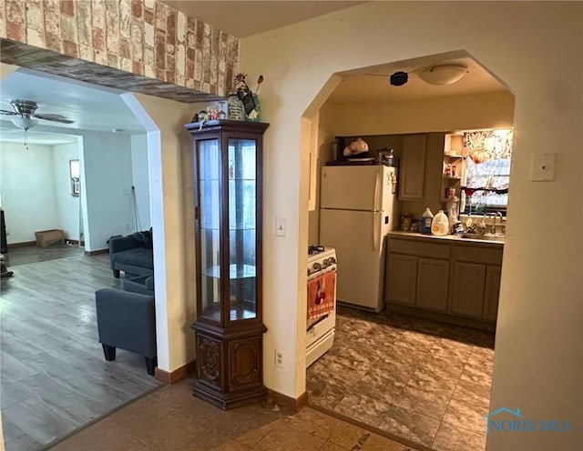 interior space featuring white appliances, ceiling fan, and sink