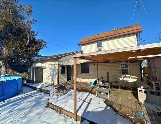 snow covered property with a swimming pool and a fire pit