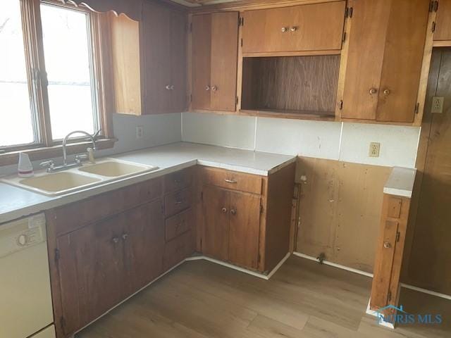 kitchen with light wood-type flooring, dishwasher, a healthy amount of sunlight, and sink