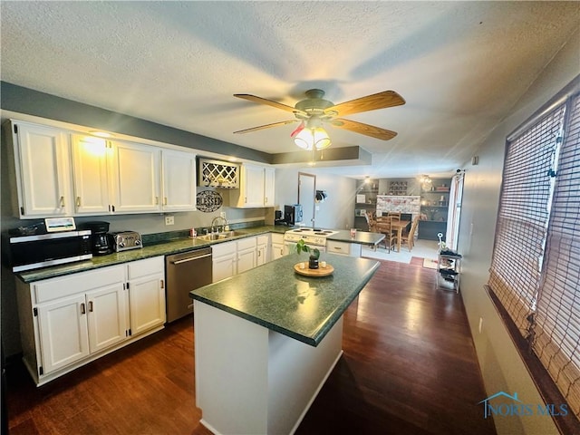 kitchen featuring dark wood-type flooring, ceiling fan, appliances with stainless steel finishes, white cabinetry, and kitchen peninsula