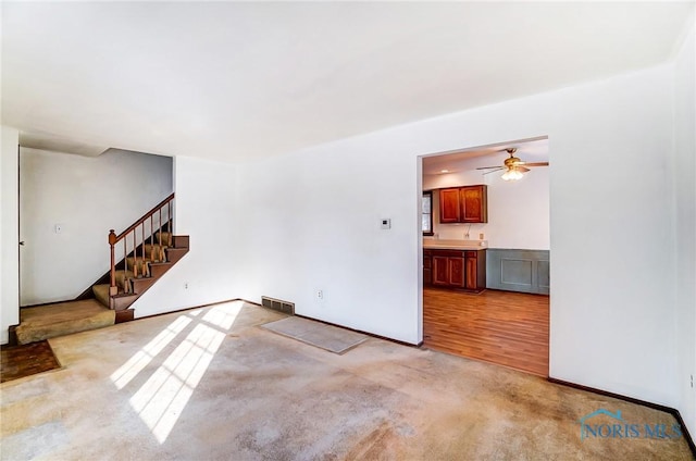 unfurnished living room with light colored carpet and ceiling fan