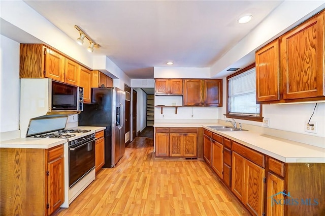 kitchen featuring sink, stainless steel fridge, gas range gas stove, and light hardwood / wood-style flooring