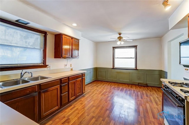 kitchen featuring sink, ceiling fan, white gas stove, and light hardwood / wood-style floors