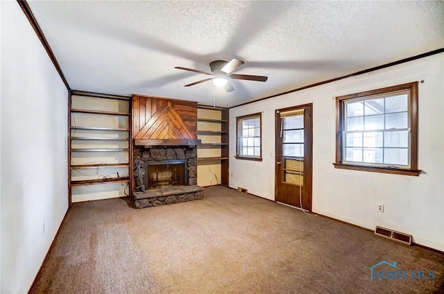 unfurnished living room with ceiling fan, dark colored carpet, a fireplace, and a textured ceiling