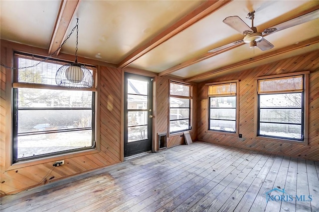 unfurnished sunroom with ceiling fan, a wealth of natural light, and lofted ceiling with beams