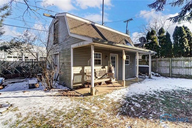 snow covered rear of property featuring a porch