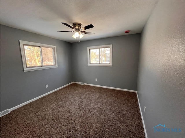 spare room featuring a textured ceiling, ceiling fan, and carpet