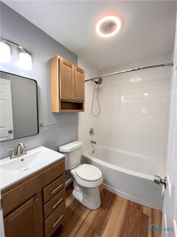 full bathroom featuring hardwood / wood-style flooring, vanity, tiled shower / bath combo, and toilet