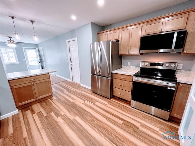 kitchen with pendant lighting, ceiling fan, appliances with stainless steel finishes, light stone counters, and light hardwood / wood-style floors