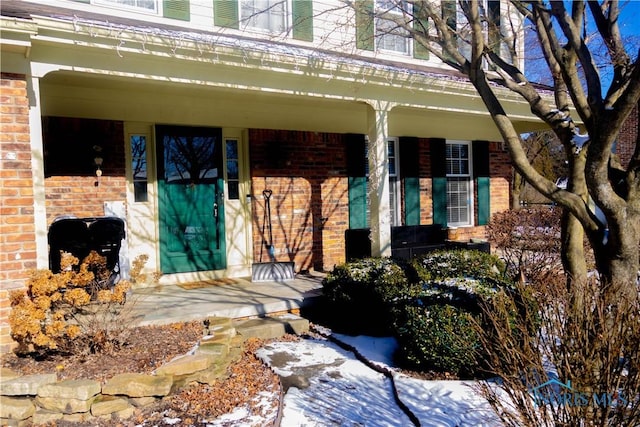 snow covered property entrance featuring a porch