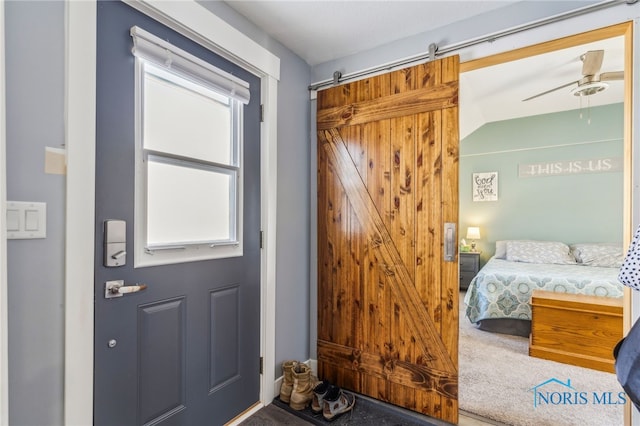 doorway to outside with ceiling fan, a barn door, vaulted ceiling, and plenty of natural light