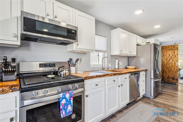 kitchen with wooden counters, sink, appliances with stainless steel finishes, dark wood-type flooring, and white cabinets