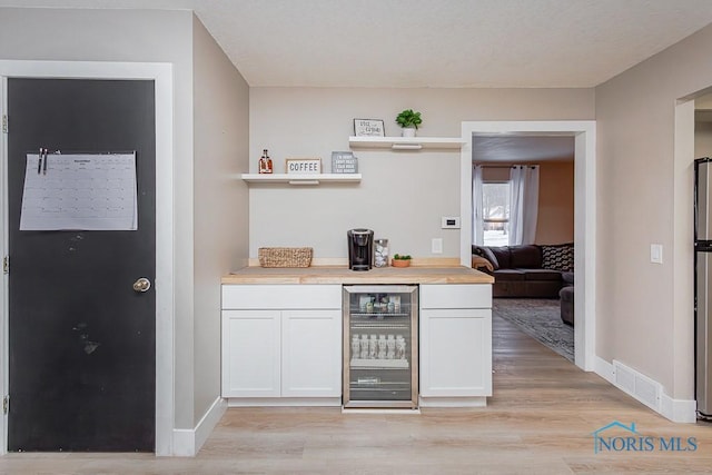 bar featuring white cabinets, beverage cooler, and light hardwood / wood-style flooring