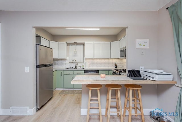 kitchen featuring white cabinets, stainless steel appliances, sink, a kitchen breakfast bar, and kitchen peninsula