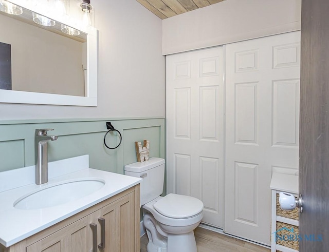 bathroom with hardwood / wood-style floors, toilet, vanity, and wood ceiling