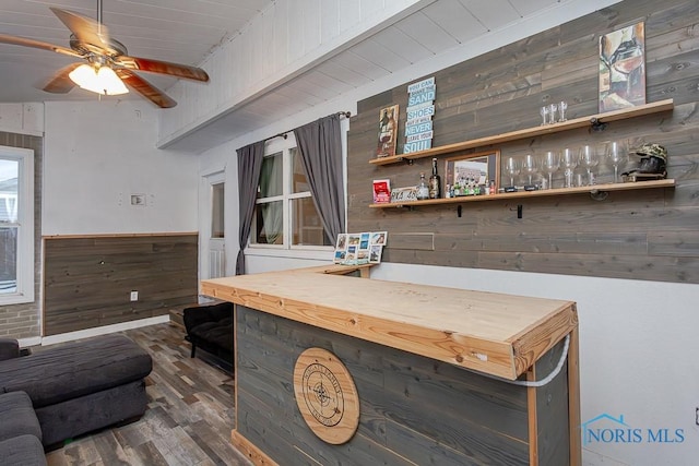 bar with ceiling fan, hardwood / wood-style floors, wood walls, and beamed ceiling