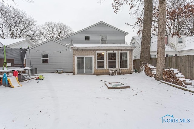 snow covered property featuring central AC unit and a trampoline