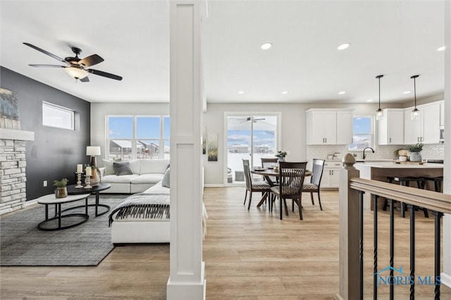 living room featuring ceiling fan, light wood-type flooring, a fireplace, and sink