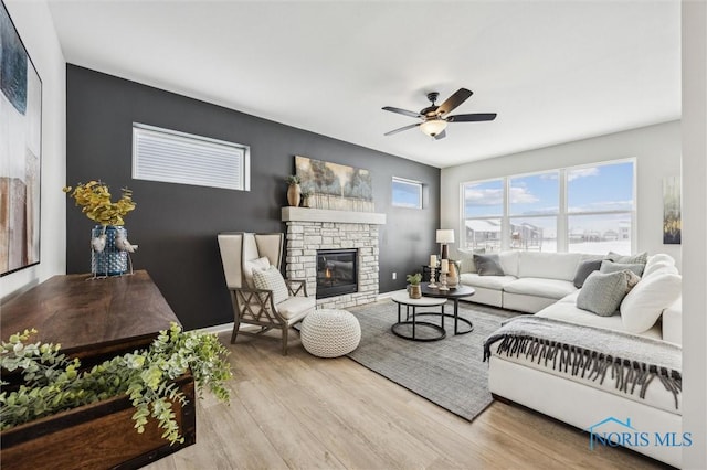 living room with ceiling fan, a fireplace, and light hardwood / wood-style flooring