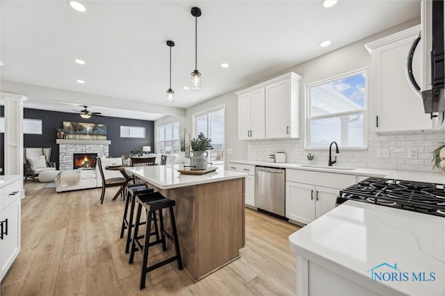 kitchen with decorative light fixtures, appliances with stainless steel finishes, white cabinetry, and a kitchen island