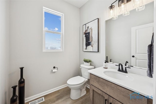 bathroom with toilet, vanity, and wood-type flooring