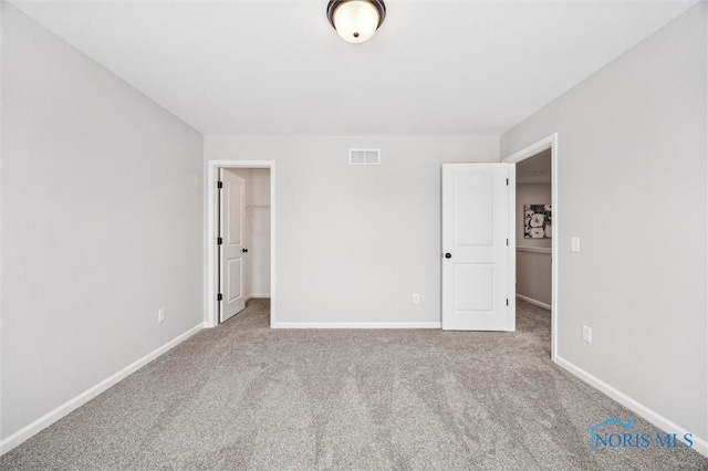 unfurnished bedroom featuring carpet floors, a closet, and a spacious closet