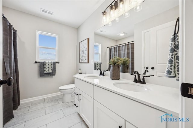 bathroom featuring a wealth of natural light, toilet, and vanity