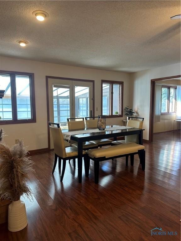 dining area with dark wood-type flooring and a textured ceiling