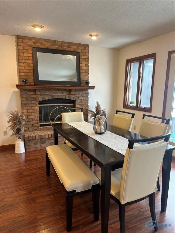 dining space featuring a textured ceiling, a fireplace, and wood-type flooring