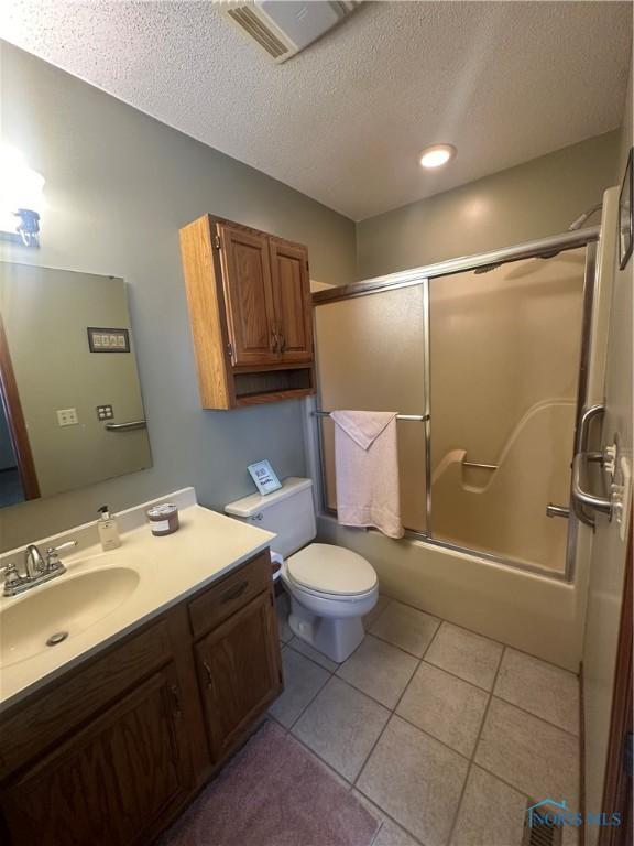 full bathroom with toilet, vanity, tile patterned floors, enclosed tub / shower combo, and a textured ceiling