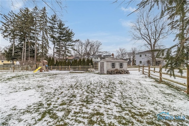 yard covered in snow featuring a shed and a playground