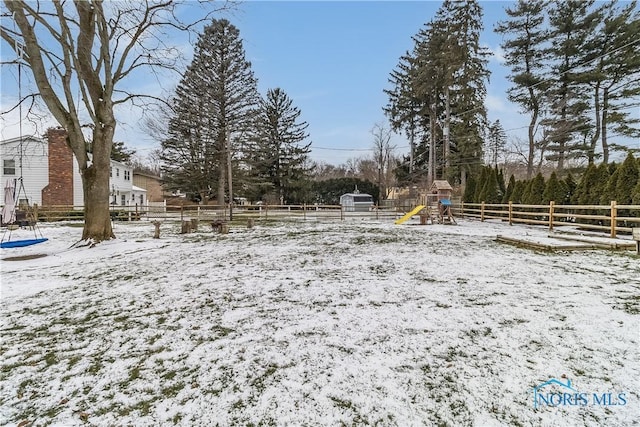 yard covered in snow with a playground