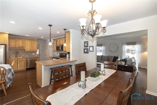 dining space with a chandelier, crown molding, dark hardwood / wood-style floors, and sink