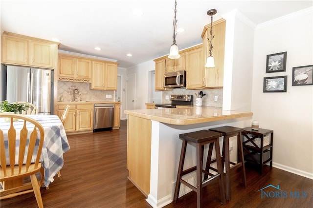 kitchen featuring kitchen peninsula, appliances with stainless steel finishes, a kitchen breakfast bar, dark hardwood / wood-style flooring, and sink