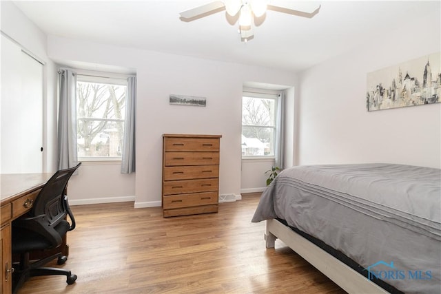 bedroom featuring ceiling fan, a closet, light hardwood / wood-style floors, and multiple windows