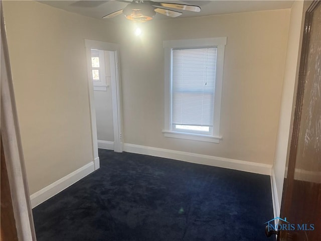 unfurnished room featuring ceiling fan and dark carpet