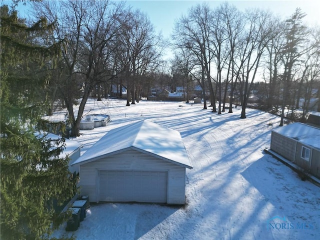 snowy yard featuring a garage and an outbuilding