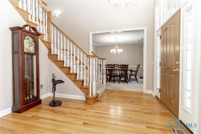 entrance foyer featuring crown molding, a chandelier, and light wood-type flooring