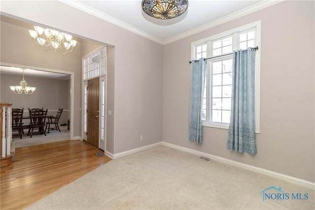 spare room with hardwood / wood-style flooring, crown molding, and a chandelier