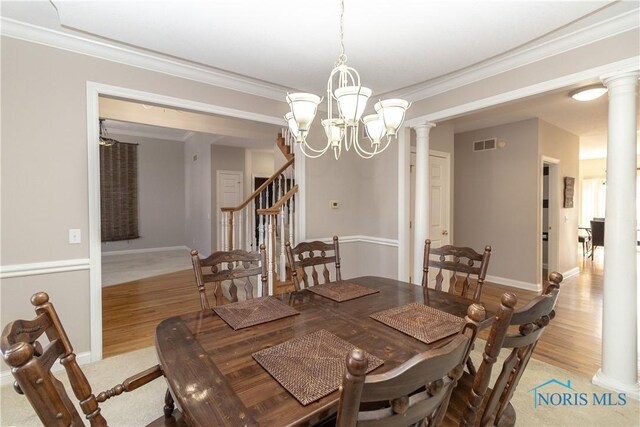 dining room featuring light wood-type flooring, ornate columns, ornamental molding, and an inviting chandelier