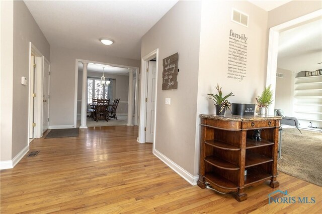 corridor with an inviting chandelier and light hardwood / wood-style floors